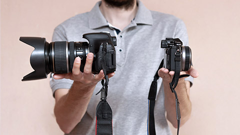 Man holding DSLR and mirrorless cameras