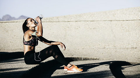 A person drinking water after a run in a hot day