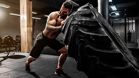 A person working out in a gym lifting a tractor tyre