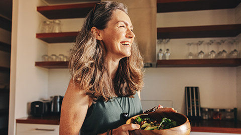 A happy person with a bowl full of assorted vegetables