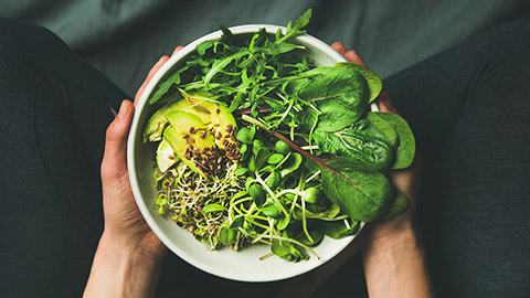 A close view of a person holding a bowl of raw vegetables