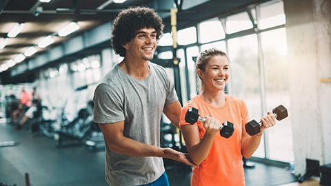 A young trainer helping a client in a modern gym