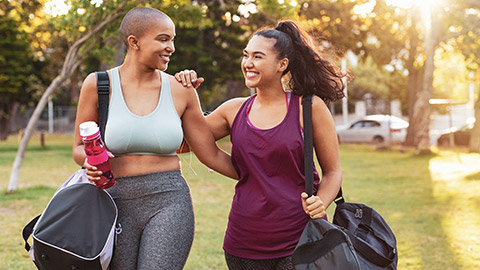 2 smiling young women heading to workout at the gym