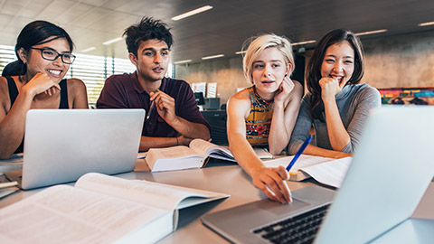 College students using laptop while sitting at table.