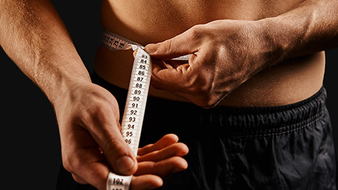 A shirtless male measuring his waste