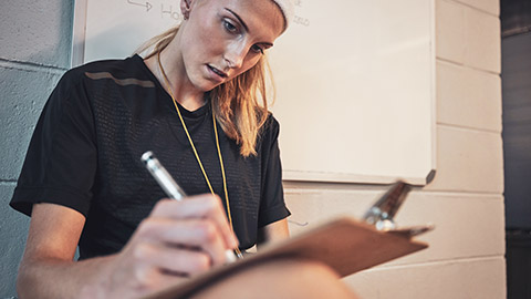 A trainer writing notes on a clipboard