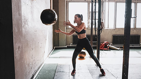 A person throuwing a medicine ball in a gym