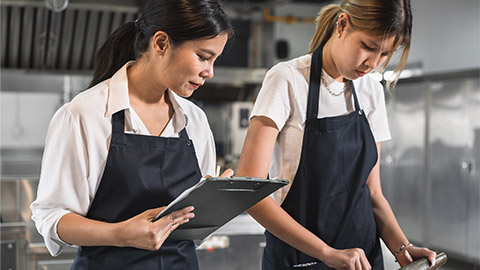 Asia woman assistant chef holding clipboard checking woman teenager cooking