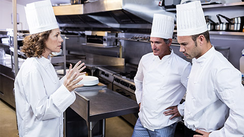 Upset head chef talking to her team in commercial kitchen