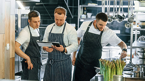 Looking at the documents. Kitchen workers is together preparing the food.