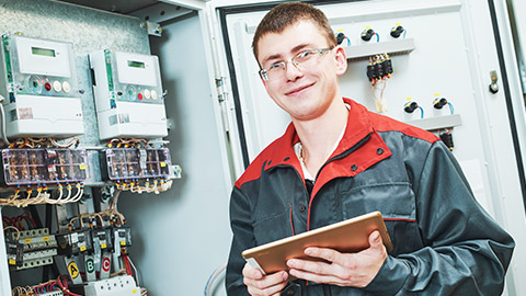 A smiling, professional electrician on a work site