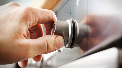 A close view of a hand turning on an appliance