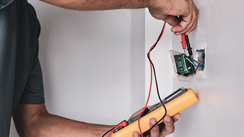 An electrician using a multimeter to check a switch