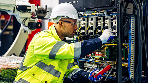 An electrician working on a machine in a factory