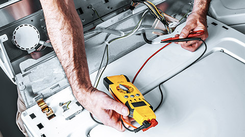 Technician repairing washing machine with tools