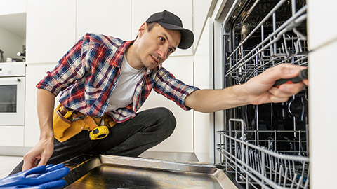 repairman fixing malfunctioning kitchen dishwasher problem