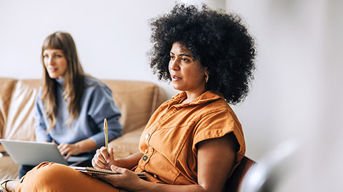 Ethnic businesswoman making notes while sitting in a meeting with her colleague.