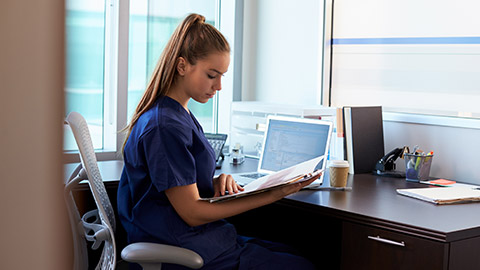 A health care worker reading information at a desk