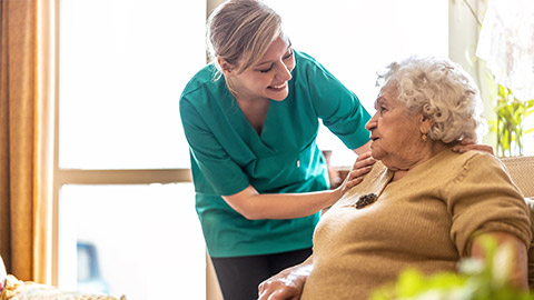 Friendly nurse supporting an elderly lady