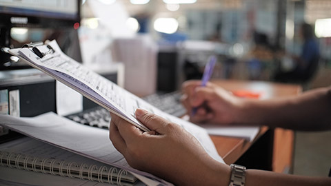 A close view of a person writing on a clipboard