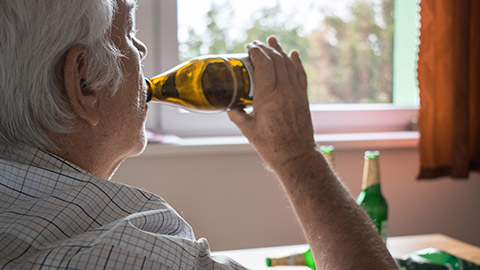 An elderly person drinking alcohol