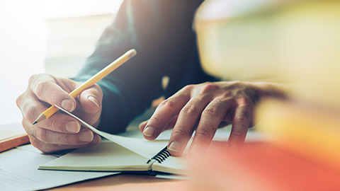 A close view of a person writing on a notepad