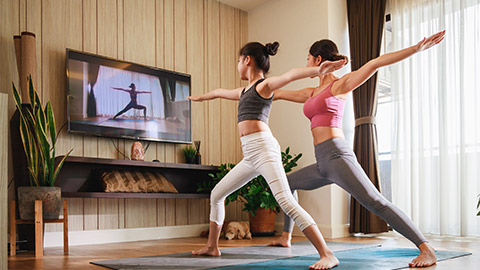 Asian woman and Little girl practicing yoga from yoga online course via smart TV at home