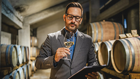 Adult man winemaker hold glass and drink wine stand