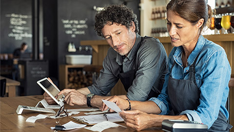 Man and woman sitting in cafeteria discussing finance for the month.