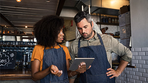 Curious colleagues wearing aprons, discussing finances