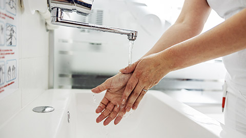 Closeup of lab assistant washing her hands while standing in laboratory.