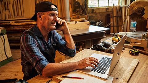 A supervisor in a workshop typing on a laptop