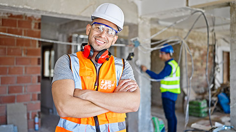 A supervisor smiling at the camera with coworker behind