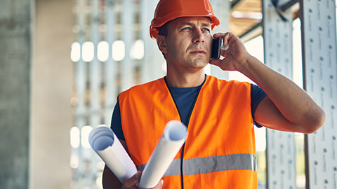 A construction worker talking on a phone