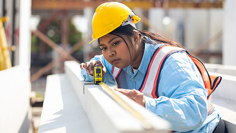 A construction worker using a measuring tape