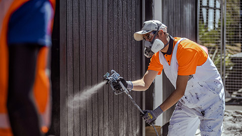 A painter spraying the outside of a house