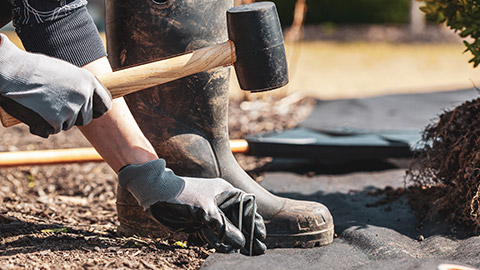 A person using a mallet to drive in stakes