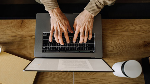 Top-down view of a person typing on a laptop