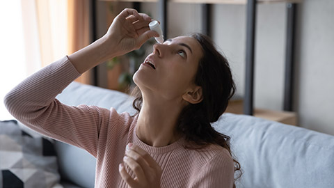 A person putting in eye drops