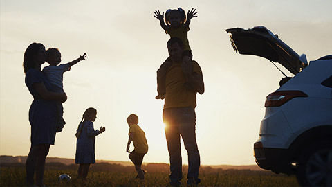 happy family. children stand together next to the car silhouette of the sunset in the park. family dream concept. happy family standing with sunlight, back watching the journey in travel the park