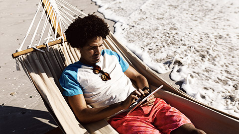 A person relaxing in a hamok with a tablet