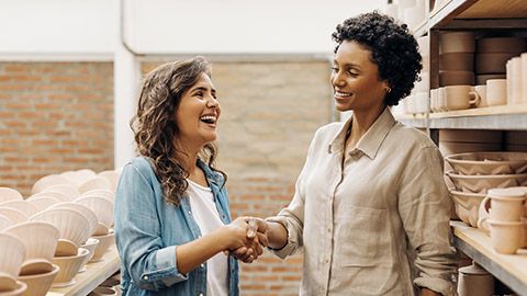 Happy female ceramists shaking hands in agreement.