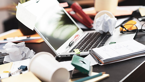 A cluttered desk and laptop