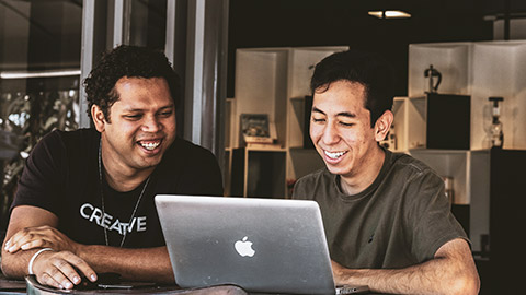 2 colleagues sitting at a desk working on a laptop