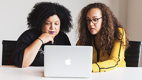 A youth worker and client sitting at a table looking at a computer