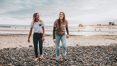 2 smiling female youths walking on a beach