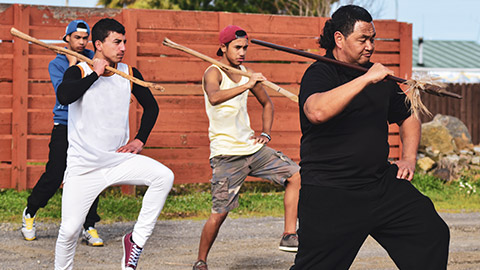 A group of young men learning maori traditions from an elder