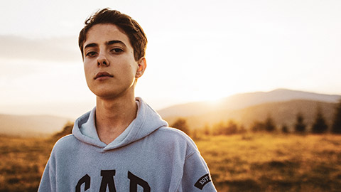 A young male with a serious look standing in a wide open outdoor space