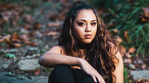 Mid-shot of a young female of maori heritage looking toward the camera with a serious expression