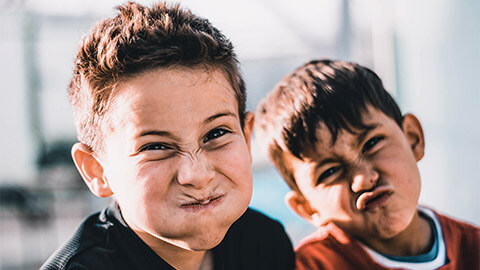 Two young children making faces at the camera, aware that they're about to have their photo taken